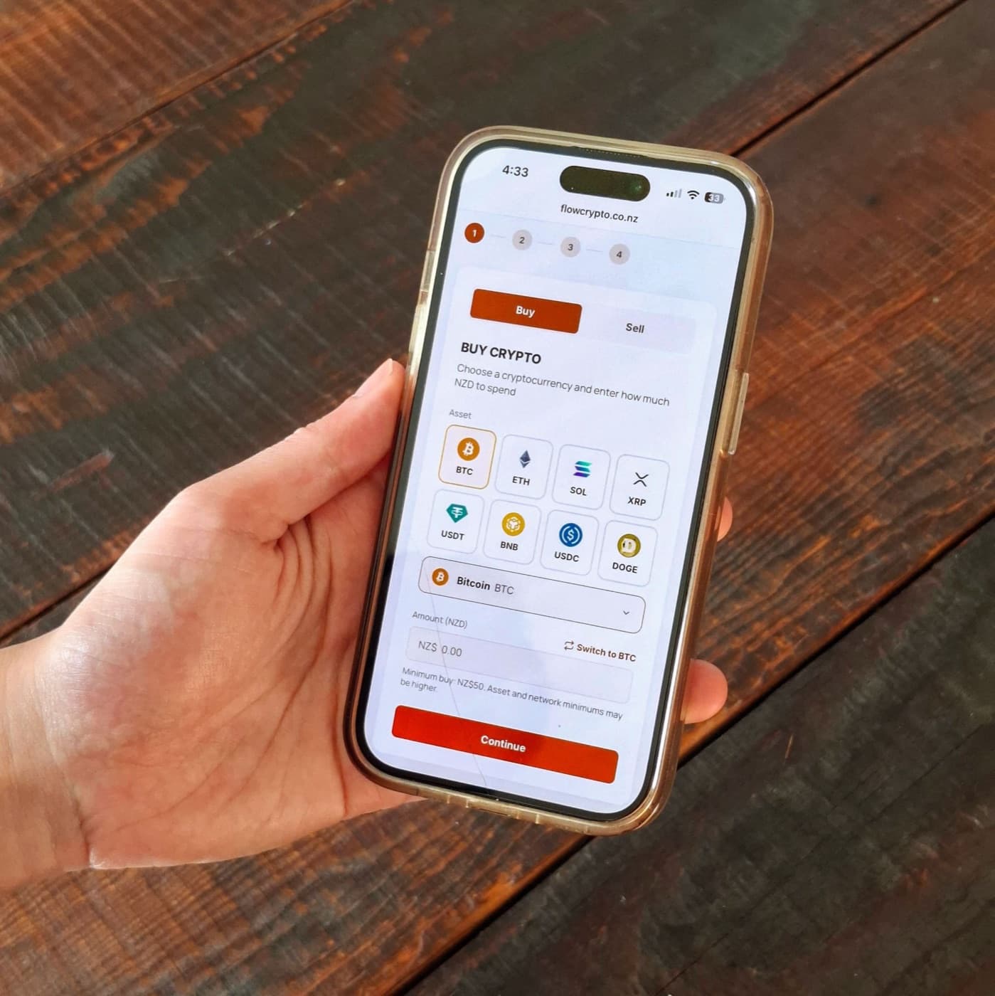 A hand holding a phone showing the Flow Crypto buy screen